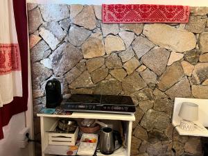 un mur en pierre derrière une table avec une cuisinière dans l'établissement Antico Casale del Poggio, à Capoterra