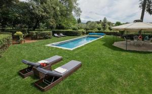 una piscina con dos tumbonas y una sombrilla en Villa Dante, en Florencia