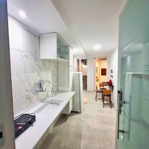 a white kitchen with a sink and a refrigerator at Casa aconchegante no centro de Remanso in Remanso