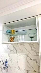 a bathroom cabinet with glasses on a marble counter top at Casa aconchegante no centro de Remanso in Remanso