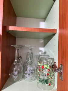three wine glasses and a jar on a shelf at Airrose two bed apartment in Wolverhampton