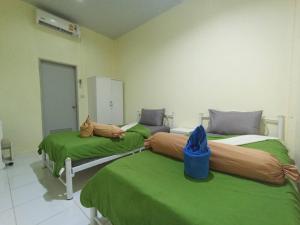 two beds in a hospital room with green sheets at บ้านสวนวารินทร์ รีสอร์ท in Pak Chong