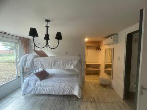 a room with three white bunk beds and a window at La Pascuala in Balneario Claromecó