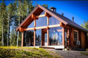a log cabin with glass windows and a roof at Arctic log house Hirvas in Hirvas