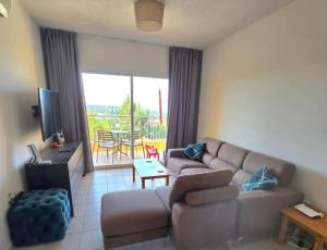 a living room with a couch and a television and a table at Tala Hills Sea View Apartment, Tala Village, Paphos in Tala