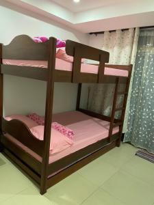a bunk bed in a room with pink sheets at Arkes Residential Condo Unit Rental in Baguio