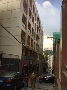 two people walking down a street in front of a building at Arkes Residential Condo Unit Rental in Baguio