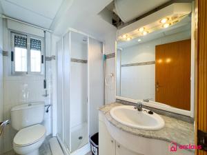 Un baño con lavabo, inodoro y espejo. en El Alba, en Benicàssim