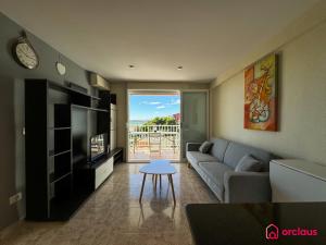 Una sala de estar con un sofá, un televisor y una mesa. en El Alba, en Benicàssim
