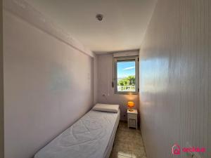 Una pequeña habitación con una cama y una ventana. en El Alba, en Benicàssim