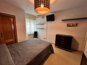 a bedroom with a bed and a television and a chandelier at Alojamiento MB Baza in Baza