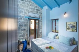 a bedroom with a bed and a stone wall at Phaistos Villas in Sívas