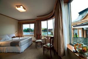 Habitación de hotel con cama y ventana grande en Hotel Naguilan, en Valdivia