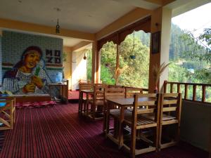 una sala da pranzo con tavolo, sedie e un dipinto di MOZO Inn&Cafe Jibhi a Banjār