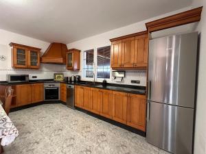 a kitchen with wooden cabinets and a stainless steel refrigerator at Casa Tortuga in Tarajalejo