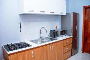 a kitchen with a sink and a stove and a microwave at Appartement meublé de standing - 2 Chambres in Abomey-Calavi