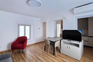a living room with a table and a red chair at Monolocale centro storico in Novara