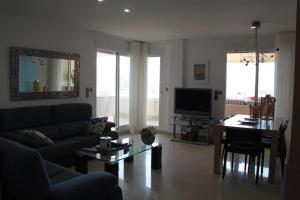 a living room with a couch and a table and a television at Ático Dos Bahías in Águilas