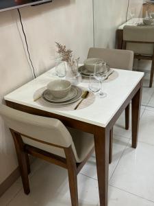 a white table with plates and glasses on it at Rustic Elegance New One Bedroom One Uptown Free parking in Manila