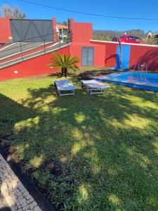 a yard with a pool and two benches in the grass at Vila Henrique Country Cottage in Fajã da Ovelha