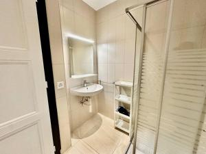 a white bathroom with a sink and a shower at Cosy apartment in Lausanne in Montagibert