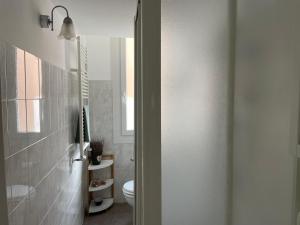 a white bathroom with a toilet and a window at In Piazzetta in Genova