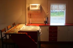 a small kitchen with a stove and a microwave at Hofdi Guesthouse in Húsavík