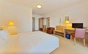 Schlafzimmer mit einem großen weißen Bett und einem Schreibtisch in der Unterkunft Sapia Hotel St. Fridolin in Bad Säckingen