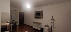 a room with a bed and a television on a wall at Hospedaria Caminho da Roça in Gonçalves