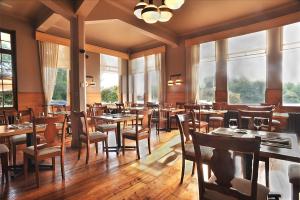 un restaurante con mesas y sillas de madera y ventanas en Hotel Naguilan, en Valdivia