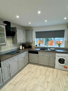 a kitchen with white cabinets and a dishwasher at Florina s House 4 Bedrooms Villa in Rugeley