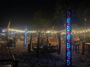 un groupe de personnes assises à des tables sous une série de lumières dans l'établissement Vitamin sea beach cabana & hostel, à Nilaveli