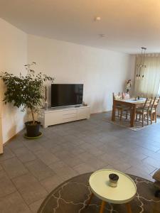 a living room with a flat screen tv and a table at Gemütliche, sonnendurchflutete Ferienwohnung in Bodenseenähe am Säntisblick in Herdwangen-Schönach
