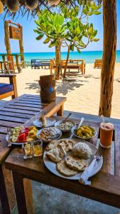 a table with plates of food on the beach at Vitamin sea beach cabana in Nilaveli