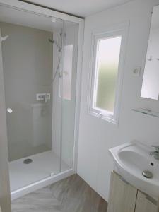 Un baño blanco con ducha y lavabo. en Mobil home, camping 4* Lac privé, en Gastes