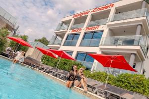 two women in bathing suits sitting in a swimming pool next to a hotel at Design-Beachresort - with Pool - first line to the sea in Maslenica
