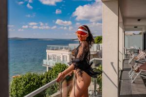 a woman standing on a balcony overlooking the ocean at Design-Beachresort - with Pool - first line to the sea in Maslenica