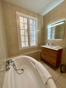 a bathroom with a bath tub and a sink at Mermoz Vue Mer, Parking in Deauville +16 photos