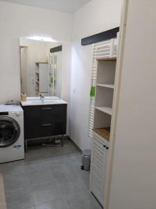 a bathroom with a sink and a washing machine at Hébergement Verneuil tout confort neuf 68m carré in Verneuil-sur-Seine