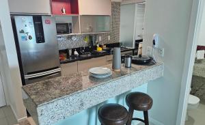 eine Küche mit einer Theke mit Hockern und einem Kühlschrank in der Unterkunft Ap70 m2 condomínio luxo Costa Espanha- Salvador- pré Carnaval -Réveillon em praia exclusiva- Vista Mar in Salvador