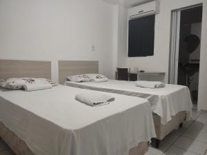 Dos camas en una habitación con paredes blancas. en Melquiades Hotel, en Patos