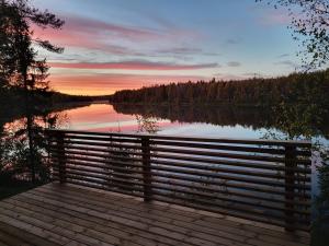 Un banco en un muelle cerca de un lago al atardecer en Villa Sol Del Luosto, en Luosto