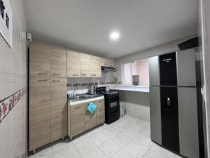 a kitchen with wooden cabinets and a black refrigerator at Moderno y acogedor apartamento - Paipa Parque principal in Paipa