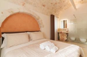 a bedroom with a large white bed with an archway at PETRA ANTIQUA in Locorotondo