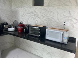 a kitchen counter with a toaster oven and a microwave at Casa Souza in Ilhéus
