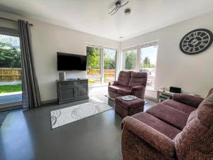 a living room with a couch and two chairs and a tv at Well Designed Bungalow In The Seaside Resort Of Hemsby, Ref 99011Og in Great Yarmouth