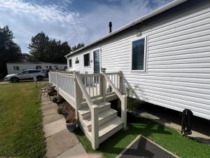 a white mobile home with a porch and stairs at Stunning Lodge Boasting Large Decking Area At California Cliffs Ref 50008L in Great Yarmouth