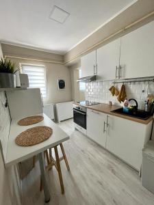 a kitchen with white cabinets and a table in it at Demure Terrace Apartment in Bucharest