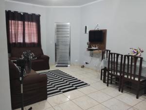 a living room with a couch and chairs and a television at Casa na praia com piscina e churrasqueira in Itanhaém