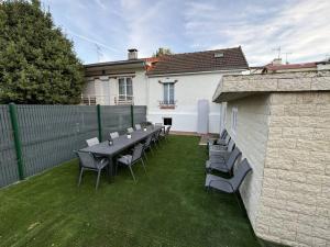 eine Terrasse mit einem Tisch und Stühlen auf dem Rasen in der Unterkunft R- Maison 6 chambres 3 min metro 10 lits PARC EXPO in Arcueil